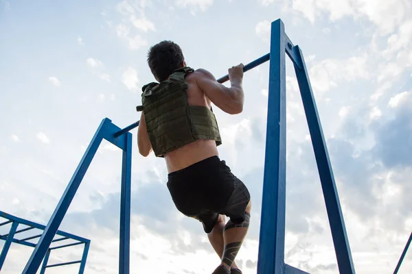 Young bearded athlete training outdoor with weighted vest,  exercise with military plate carrier
