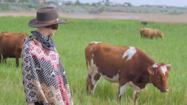 穿着披着披着披着帽子的年轻女旅行者在田野和农场里散步 — 图库视频影像