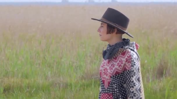 穿着披着披着披着帽子的年轻女旅行者在田野和农场里散步 — 图库视频影像