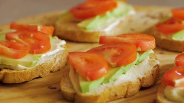 木桌上有鳄梨和西红柿的新鲜烤面包 — 图库视频影像