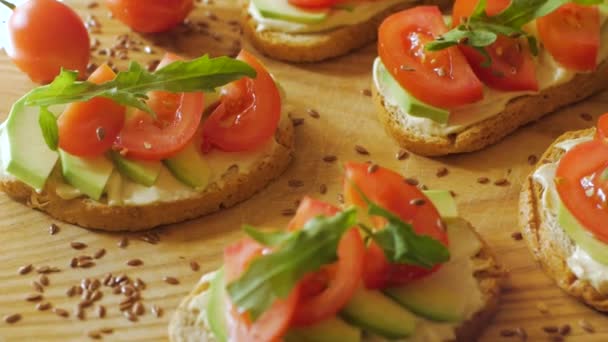 Färska Rostat Bröd Med Avokado Och Tomater Träbord — Stockvideo