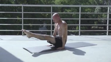 Dövmeli genç erkek balkonda açık havada yoga egzersizleri yapmak