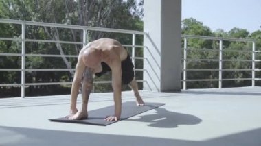 Dövmeli genç erkek balkonda açık havada yoga egzersizleri yapmak