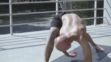 Dövmeli genç erkek balkonda açık havada yoga egzersizleri yapmak