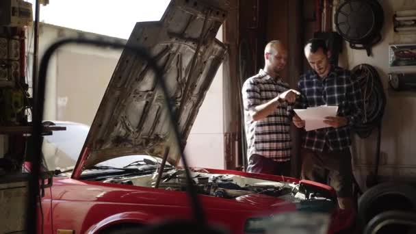 两名机械师在车库修理汽车发动机在工作间 — 图库视频影像