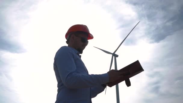 風力タービンで見ているヘルメットの男性労働者 — ストック動画
