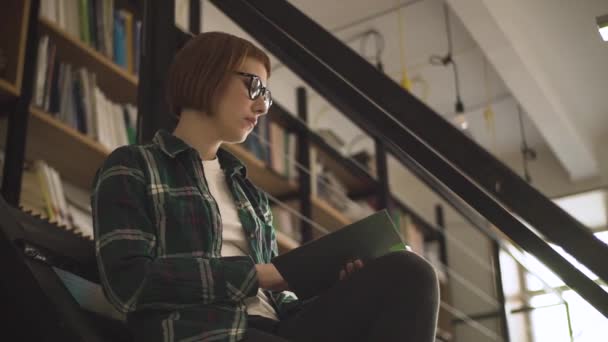 Jeune Rousse Femme Lunettes Lire Livre Dans Bibliothèque — Video