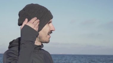 Genç erkek koşucu soğuk havalarda açık havada eğitim, sonbahar plajda atlet egzersiz