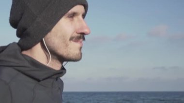 Genç erkek koşucu soğuk havalarda açık havada eğitim, sonbahar plajda atlet egzersiz