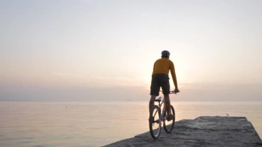 Deniz kenarında dağ bisikleti süren erkek güzel gün batımına karşı 