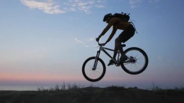 Deniz kenarında dağ bisikleti süren erkek güzel gün batımına karşı 