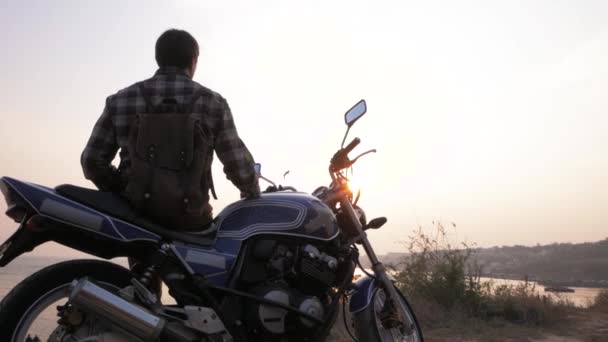 美しい夕日の間に海の近くのオートバイに座っているとヨークの男性旅行者 — ストック動画