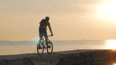 Deniz kenarında dağ bisikleti süren erkek güzel gün batımına karşı 