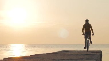 Deniz kenarında dağ bisikleti süren erkek güzel gün batımına karşı 