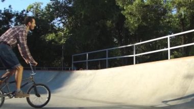 Beton kayak parkında erkek bisikleti sürüyor. 