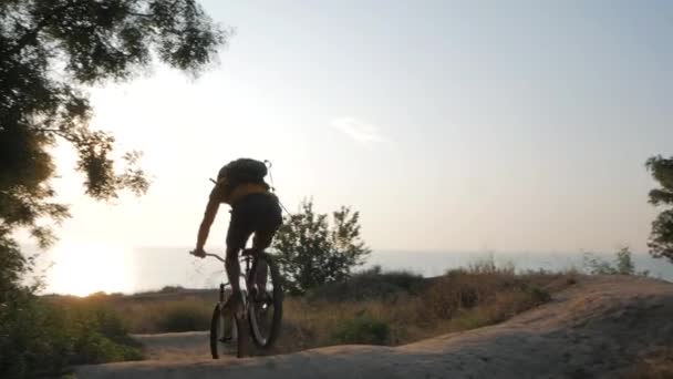 男は美しい夕日に対して海の近くのマウンテンバイクに乗る — ストック動画