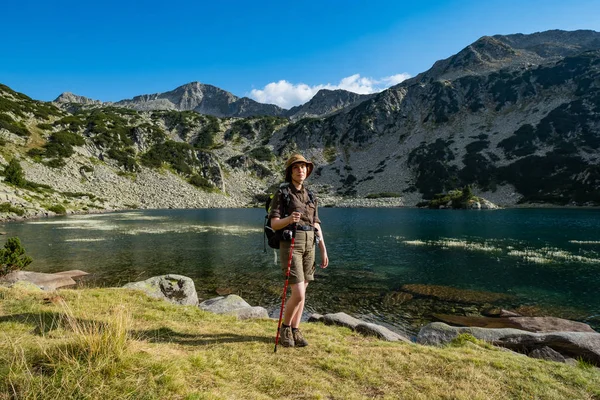 Young woman with backpack hiking in the mountains near beautiful lake