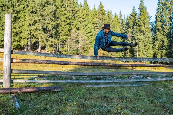 Ung Manlig Bonde Jeansjacka Och Cowboyhatt Hoppar Över Staketet — Stockfoto