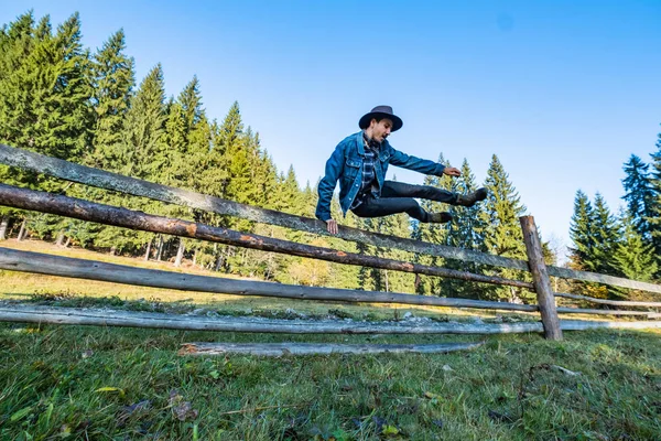 Ung Manlig Bonde Jeansjacka Och Cowboyhatt Hoppar Över Staketet — Stockfoto