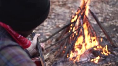 Genç erkek gezgin sonbahar ormanında tek başına gitar çalıyor. Parkta akustik gitarlı müzisyen portresi.