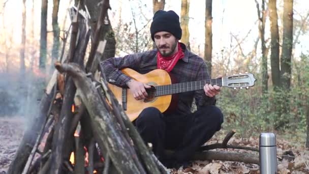 年轻的男性旅行者独自在秋天的森林里弹吉他 公园外带声吉他的音乐家肖像 — 图库视频影像