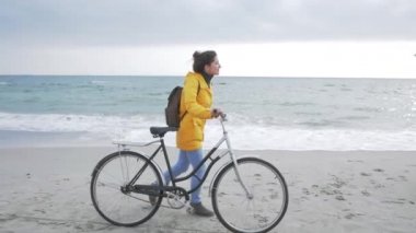 Sonbaharda ya da kış plajlarında retro bisikletle poz veren genç seksi hippi kadın.