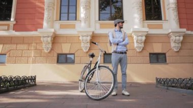 Güneşli bir günde sokaklarda bisiklet süren, modern iş adamının cep telefonuyla portresini çizen şık bir genç.