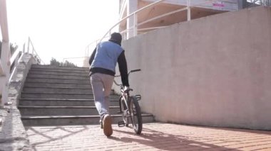 Şehirde genç bir erkek BMX bisikleti sürüyor.