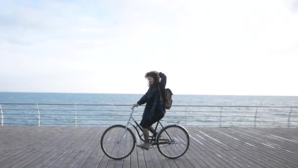 若いですStilishヒップスター女性ポージングで秋や冬のビーチでレトロな自転車 — ストック動画