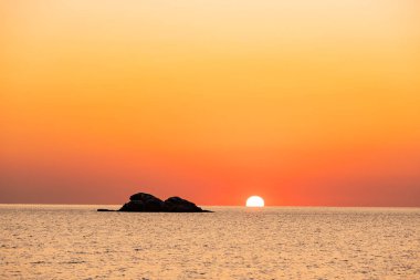 Güneşin deniz ve dağda doğduğu güzel bir manzara.