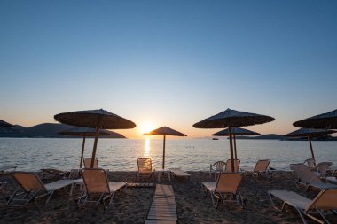 Yunanistan 'da plaj şemsiyesi, güzel gündoğumu ve yaz plajı olan manzara