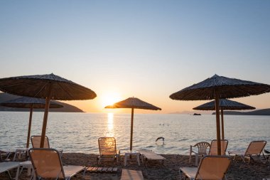 Yunanistan 'da plaj şemsiyesi, güzel gündoğumu ve yaz plajı olan manzara