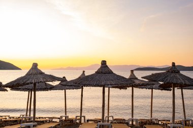 Yunanistan 'da plaj şemsiyesi, güzel gündoğumu ve yaz plajı olan manzara