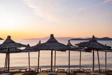 Yunanistan 'da plaj şemsiyesi, güzel gündoğumu ve yaz plajı olan manzara
