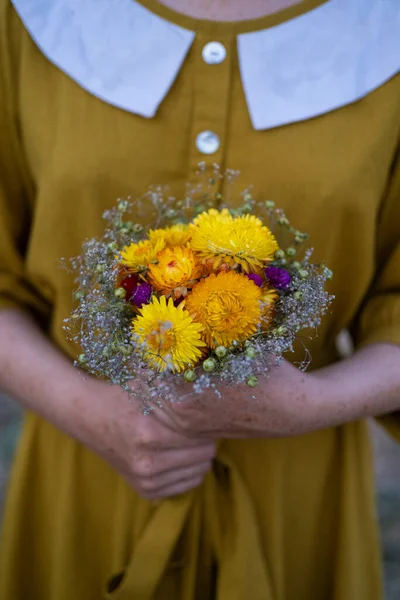 Young redhead woman with  freckles in vintage handmade dress walk in fields with flowers