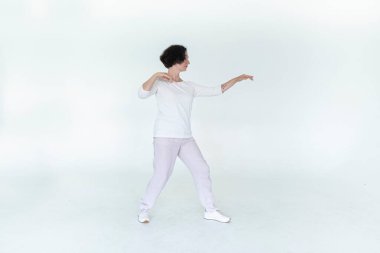 Beyaz stüdyo geleneksel Çin jimnastik salonunda qi qong antrenmanı yapan kadın.