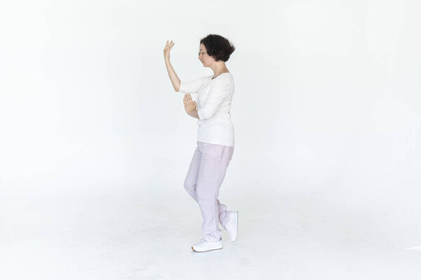 woman practicing qi qong at white studio traditional chinese gymnastics