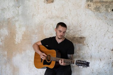 Boş odada gitarı olan genç bir erkek. Stüdyoda müzisyen ve söz yazarı yalnız.