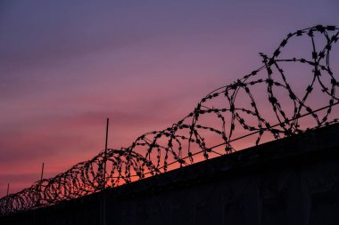 Gün batımına karşı dikenli tel silueti