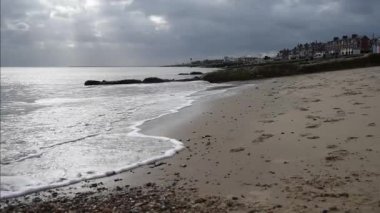 Felixstowe kumsalda bulut ile görünen güneş ışınları ile kırma dalgalar