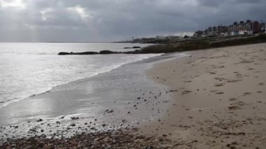 Felixstowe kumsalda bulut ile görünen güneş ışınları ile kırma dalgalar