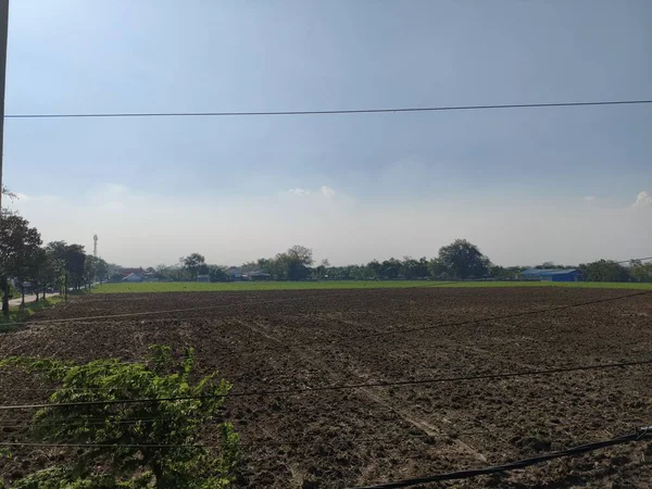 Bulutlu bir gökyüzünün altındaki kahverengi toprak tarlası.