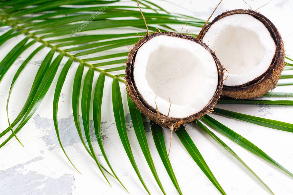 Coconut halves and leaves on white background