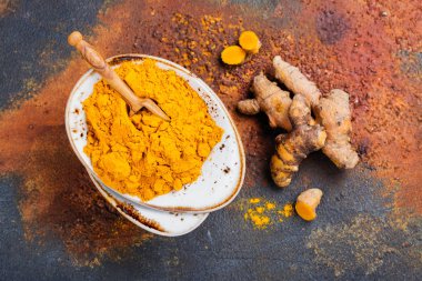 Zerdeçal tozu ve grunge arka plan üzerinde taze kök