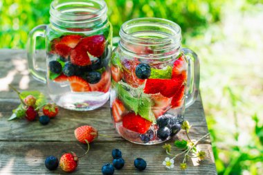 Taze yaz limonata ile nane, yaban mersini, çilek parti ya da bahçe piknik için. Doğal ışık. Ahşap masa yaz lekeler. Kopya alanı
