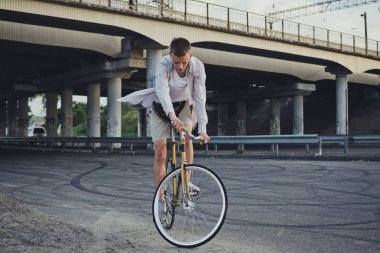 Genç yakışıklı hipster kişini Sabit vites bisiklet günbatımı sırasında