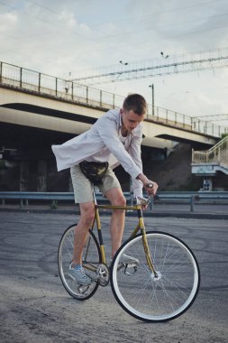 Genç yakışıklı hipster kişini Sabit vites bisiklet günbatımı sırasında