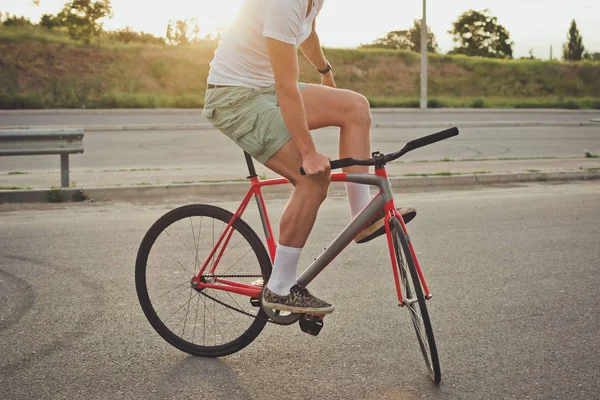 Genç yakışıklı hipster kişini Sabit vites bisiklet günbatımı sırasında yakın çekim