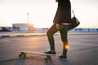 Günbatımı sırasında kişini longboard üzerinde atış yukarıya kapatmak