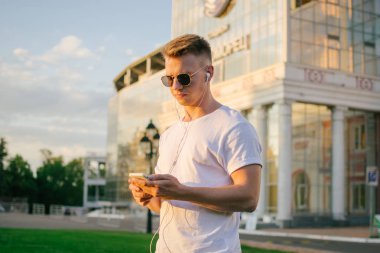 Yakışıklı genç hipster adam akıllı telefon açık havada park kullanarak